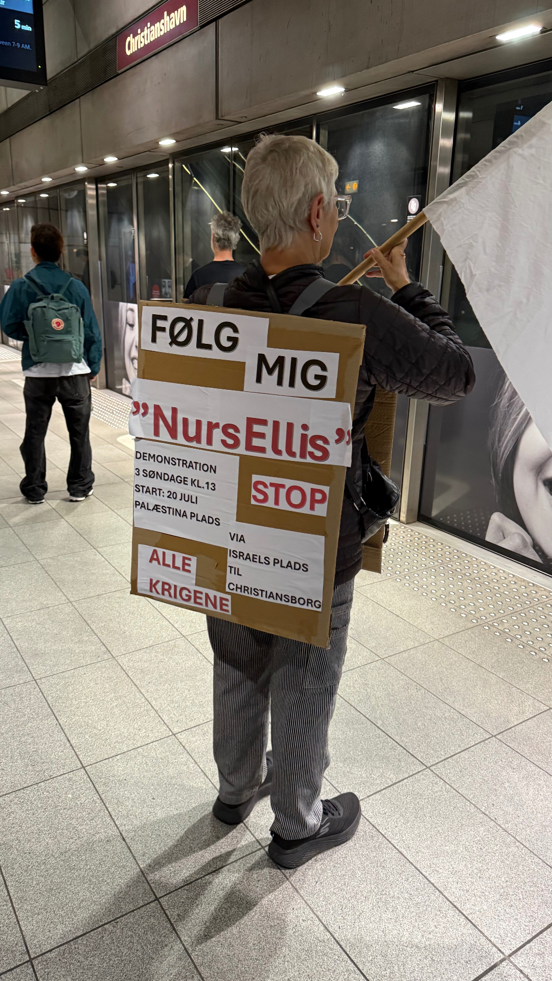 Ellis går i demonstration med skilt og fane på Christianshavn station